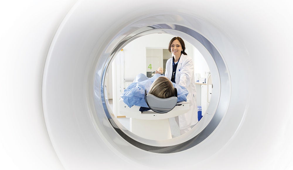Doctor assisting patient in MRI scanner.