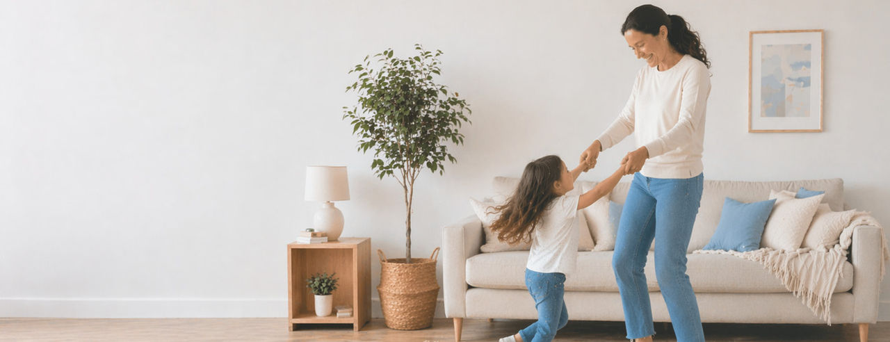 Female with daughter dancing joyfully, in everyday home environment.